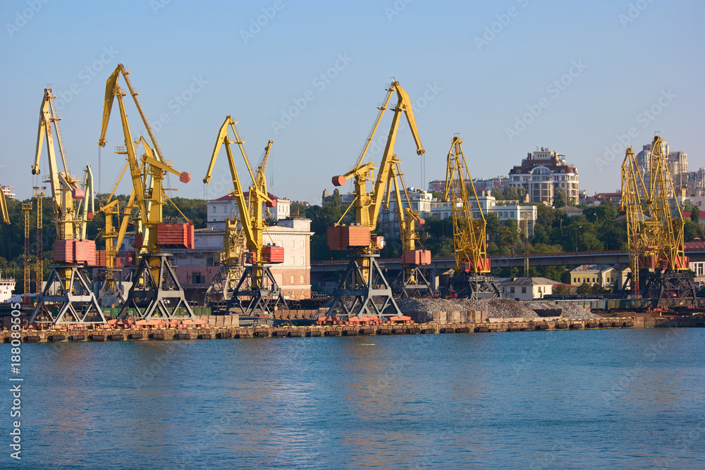 Wharf cranes with city background. Level luffing yellow cranes.