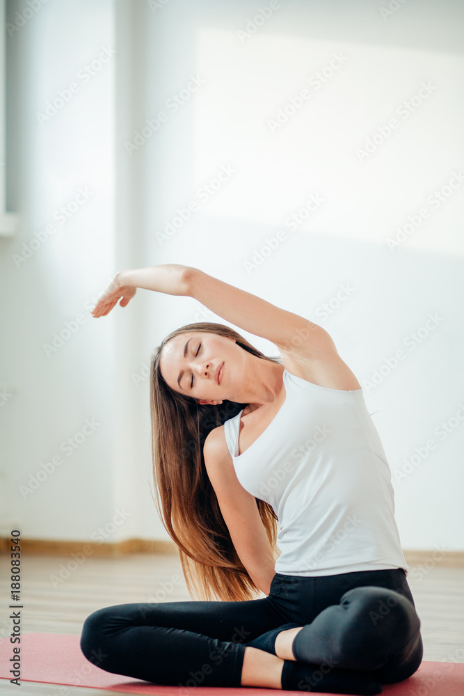 Young girl makes aerobics exercise sitting in lotus pose on mat. Healthy lifestyle, gymnastics concept Young girl makes aerobics exercise sitting in lotus pose on mat. Healthy lifestyle, gymnastics concept