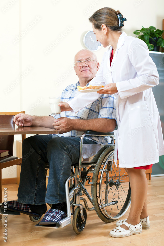  wife helping her husband in   wheelchair.