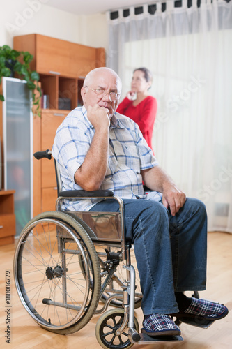 elderly husband in wheelchair with sad wife