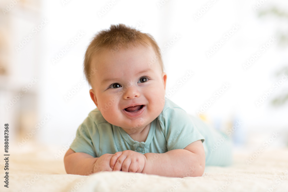 Very happy laughing baby in blue clothes lying on his belly. Very happy laughing baby in blue clothes lying on his belly.