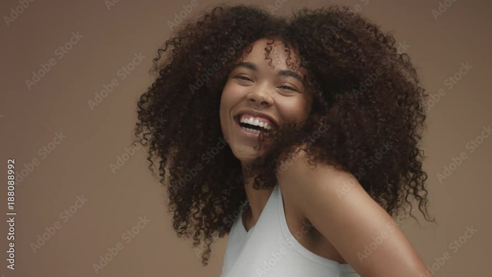 closeup slowmotion portrait of laughin black woman with curly hair in studio
