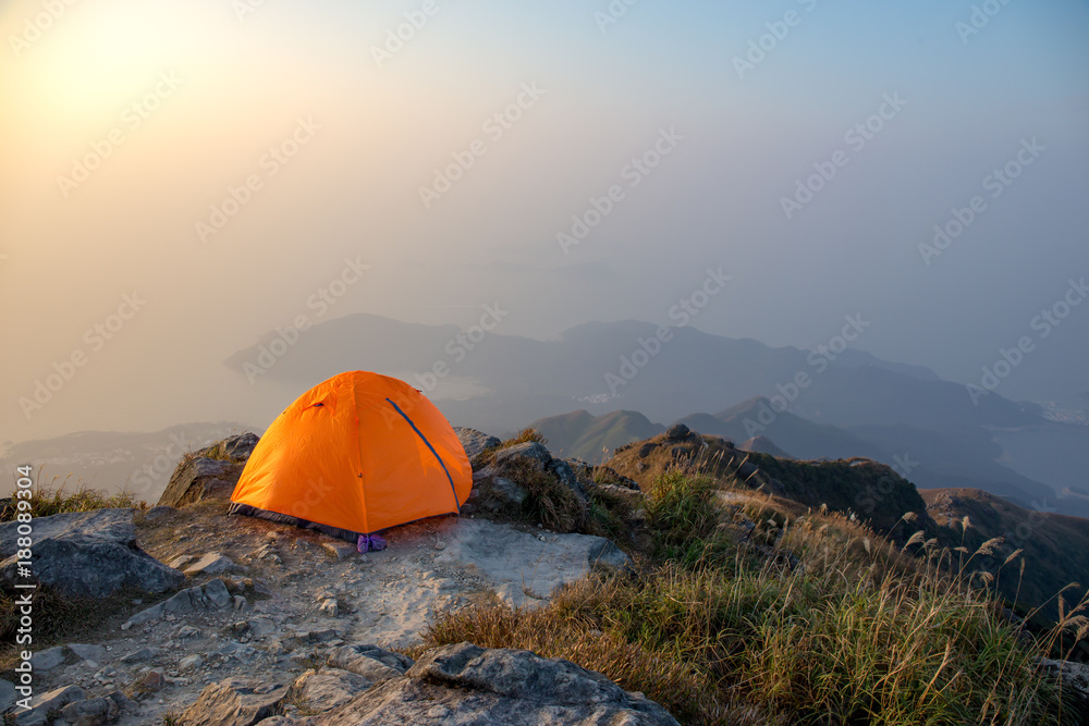 orange tent camping near cliff isolated on lantau peak, Hong Kong in sunrise and fog with copy space