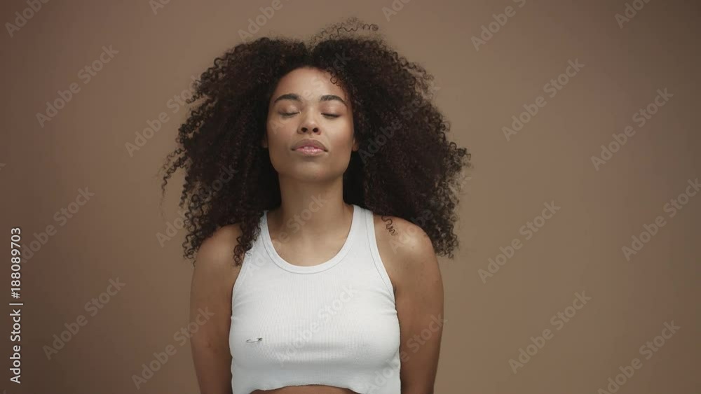 slow motion of black woman lifting head and shaking hair in studio