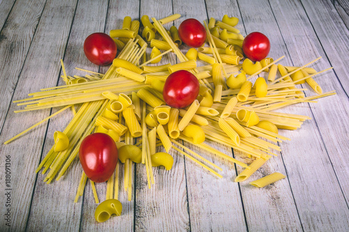 Uncooked pasta of varius kinds and red fresh tomatoes photo