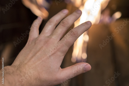 the man is warming his hand by the fire