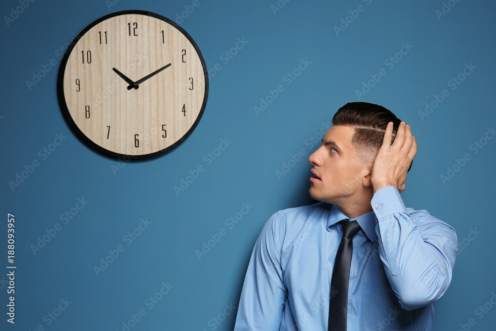 Shocked manager looking at clock hanging on wall Shocked manager looking at clock hanging on wall