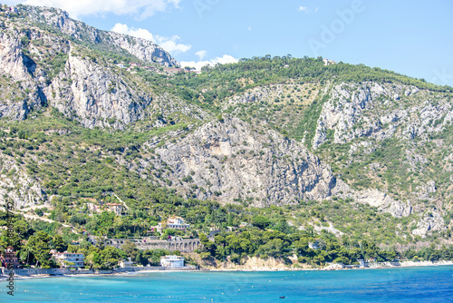 Daylight view to buildings near seashore, green trees and big rock mountains photo