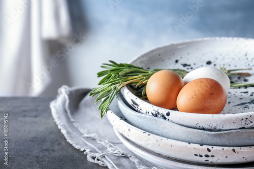 Plates with chicken eggs and rosemary on table