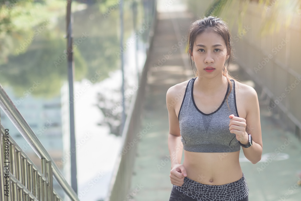 Young asian woman running on sidewalk in morning. Health conscious concept with copy space. Young sport asian woman running upstairs on city stairs. Fitness sport people and healthy lifestyle concept.