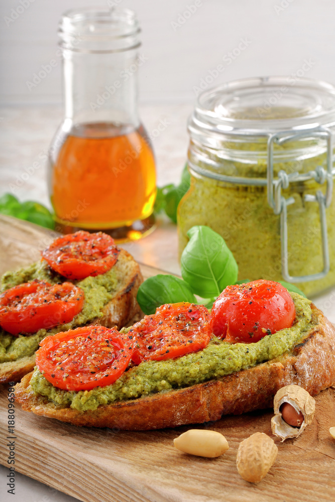 Fresh toast with pesto and roasted tomatoes on wooden background