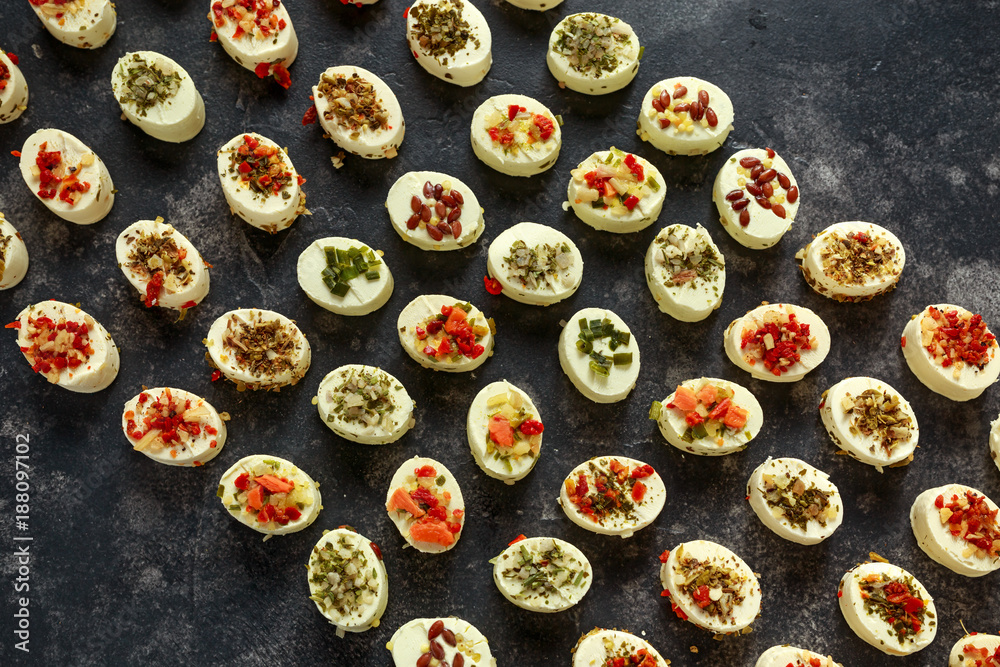 Creamy cheese bites garnished with pesto, red peppers, herbs, garlic, tomato, olives, shallots, onions and carrots. Party Finger food. Creamy cheese bites garnished with pesto, red peppers, herbs, garlic, tomato, olives, shallots, onions and carrots. Party Finger food.