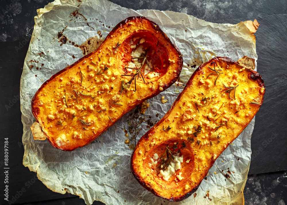 Oven baked butternut squash halves with thyme, rosemary and feta cheese drizzled with olive oil Oven baked butternut squash halves with thyme, rosemary and feta cheese drizzled with olive oil