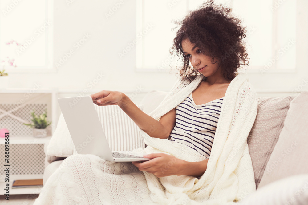 Young girl with laptop sitting on beige couch Young girl with laptop sitting on beige couch
