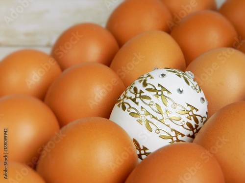 A beautiful Easter egg with patterns in a tray with ordinary eggs photo