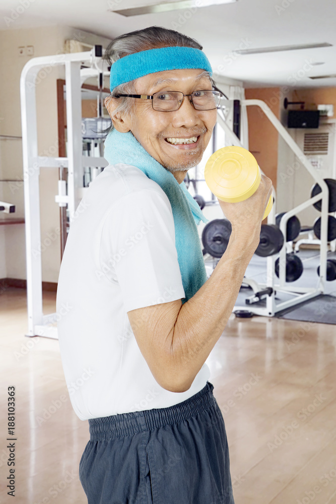 Happy elderly man exercising with a dumbbell