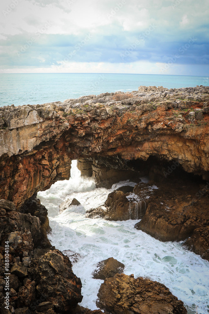 Big rock formation with a cave in the center with ocean water inside. Local known as 