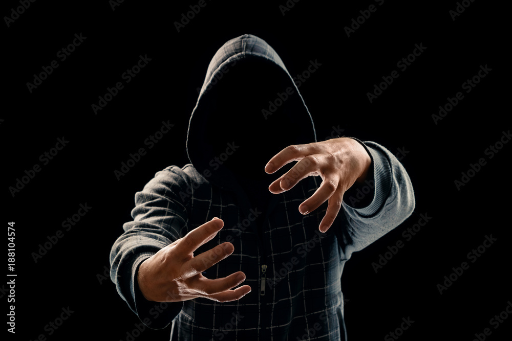 Portrait, silhouette of a man in a hood on a black background, his face is not visible. The concept of a criminal, incognito, mystery, secrecy, anonymity.