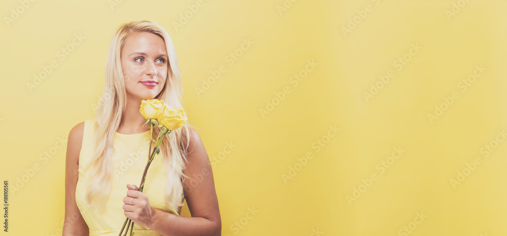 Young woman with flowers on a yellow background Young woman with flowers on a yellow background