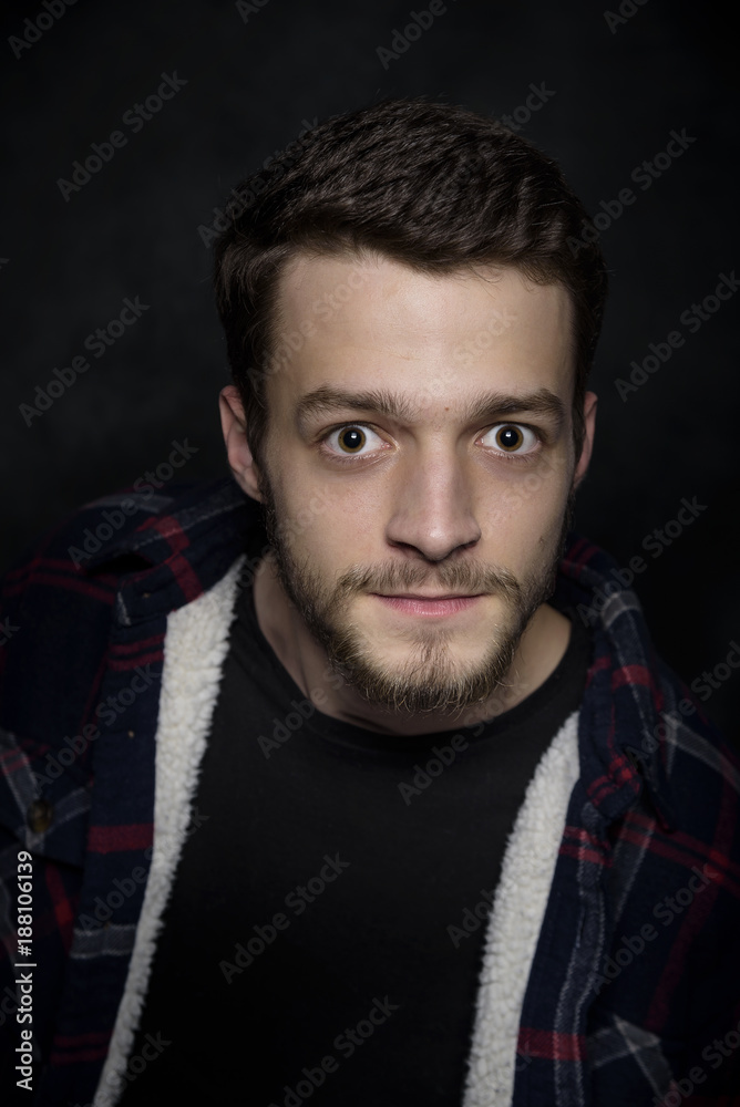 Obraz premium Portrait of a young man with a beard on a dark background.
