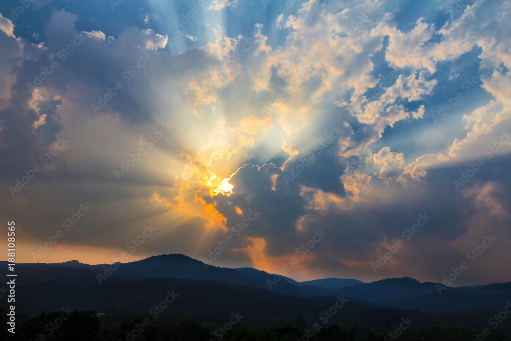 Beautiful sunrise or sunset with clouds and golden sunbeam over mountains.