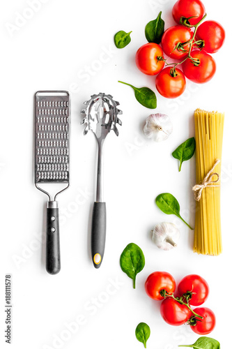 Preparing to cook pasta. Spaghetti, tomatoes, garlic, cheese grater, spoon for spaghetti on white background top view