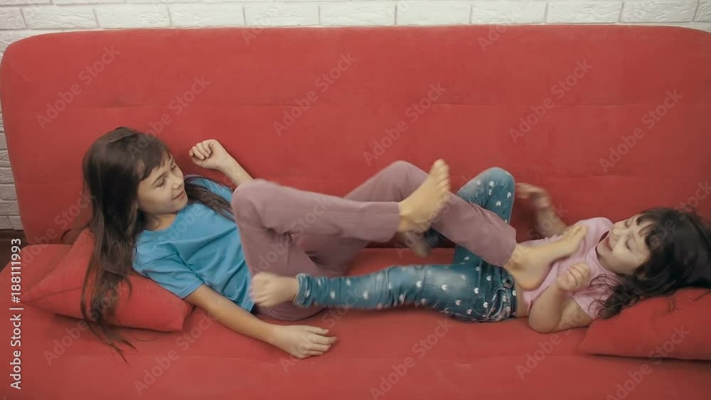 Little girls fight with their feet. Happy sisters are playing with each