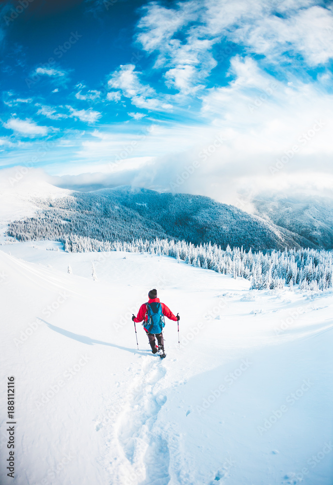 A man in snowshoes in the mountains in the winter.