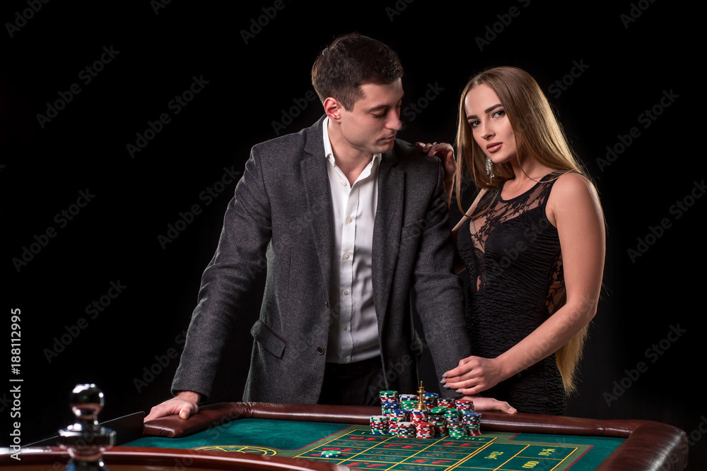 Elegant couple at the casino betting on the roulette, on a black background Elegant couple at the casino betting on the roulette, on a black background