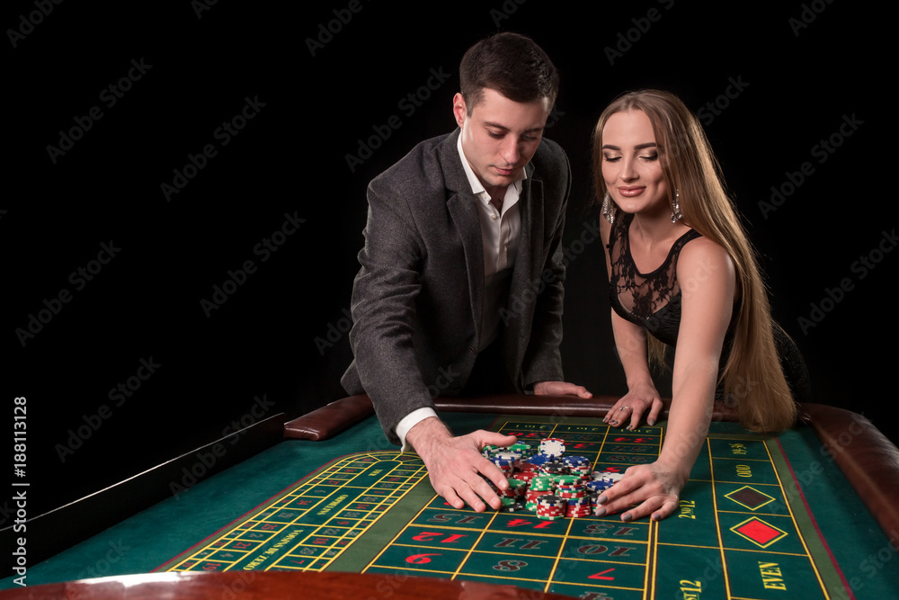 Young beautiful couple takes their winnings at the roulette table at the casino Young beautiful couple takes their winnings at the roulette table at the casino