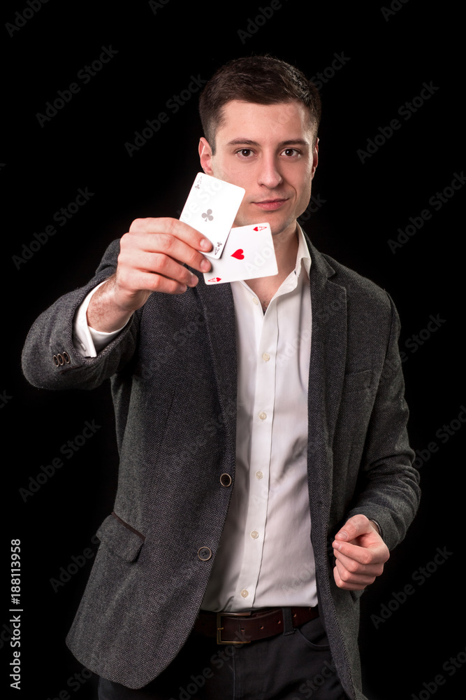 Young caucasian man wearing suit holding two aces in his hand on black background. Gambling concept. Casino Young caucasian man wearing suit holding two aces in his hand on black background. Gambling concept. Casino
