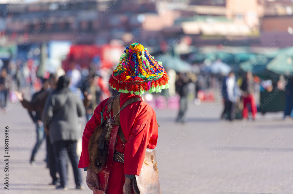 Water seller or water keeper Guerrab dressed in in typical colorful Moroccan costume at the market place in Marrakech