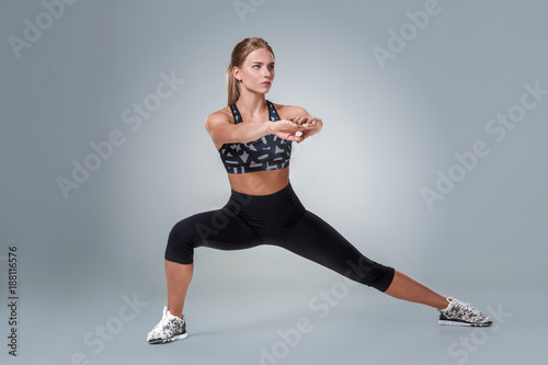 Stretching workout posture by a woman on studio gray background