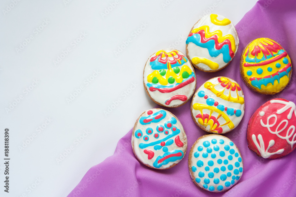 Festive cookies in the form of Easter eggs with purple napkin on a white background Festive cookies in the form of Easter eggs with purple napkin on a white background