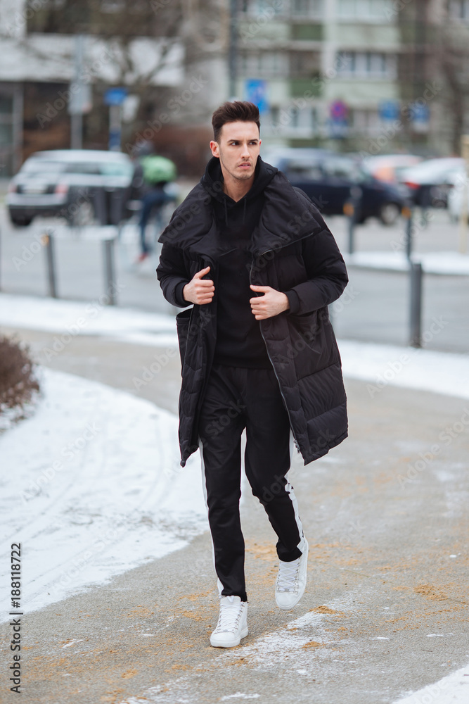 Stylish man wolk on the street. Winter cold outfit. Big jacket with white  sneakers. Blured background street. Profecional model photo. Stock Photo |  Adobe Stock