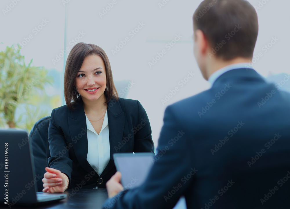 Beautiful young businesswoman conducting a job interview seated at her desk. Beautiful young businesswoman conducting a job interview seated at her desk.