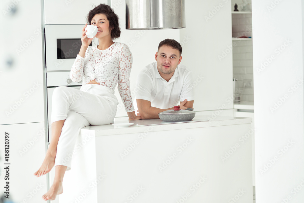 Lovely romantic couple in the white modern kitchen spending time together Lovely romantic couple in the white modern kitchen spending time together