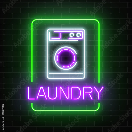 Neon glowing laundry signboard on dark brick wall background.