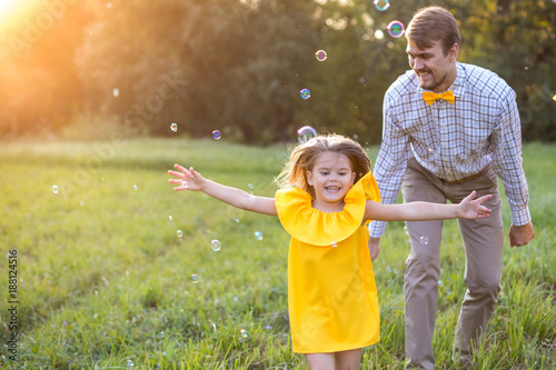 Happy family. concept - father,and child daughter having fun and playing in nature. yellow clothes. summer sunny day. in green nature together rest