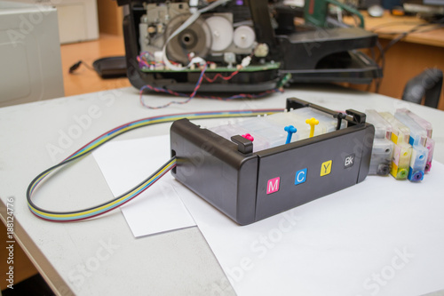 Color cartridges and continuous ink supply system on the background of the disassembled inkjet printer photo