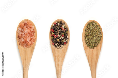 Various spices on wooden spoons isolated on white background. (pink salt, pepper, oregano)