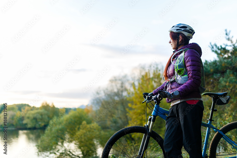 Image of girl with bicycle in helmet in autumn