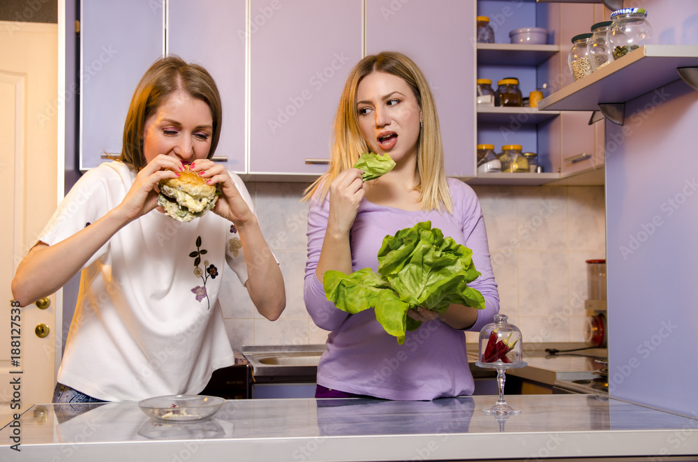 Diet funny concept, one girl eating healthy food green salad and looking at  her friend eating tasty burger Stock Photo | Adobe Stock