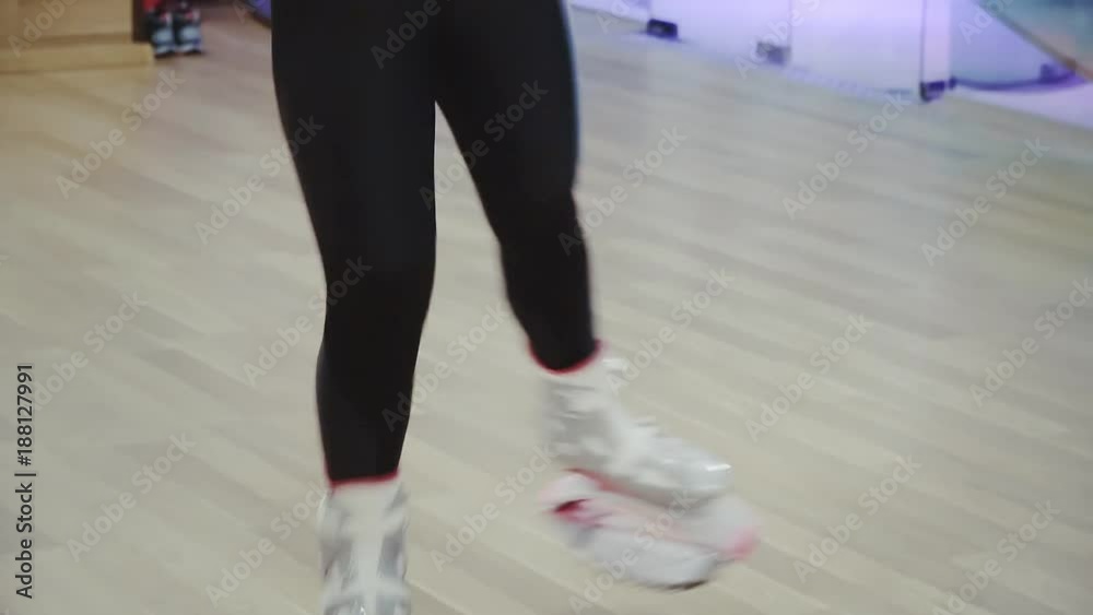 Blonde pretty young woman jumping in kangoo shoes in the gym. Blonde pretty young woman jumping in kangoo shoes in the gym.
