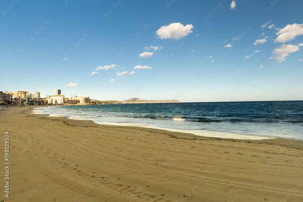 View of the deserted sandy beach and the city at sunset