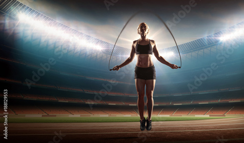 fit woman exercising with jumping rope on a stadium