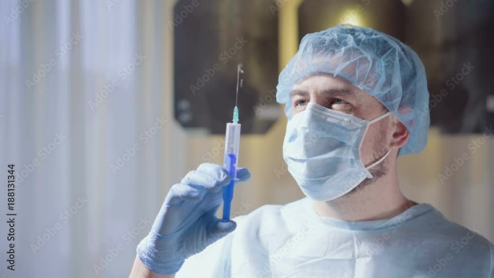Young man doctor with mask prepares a syringe on x-ray background. Medical concept. Young man doctor with mask prepares a syringe on x-ray background. Medical concept.