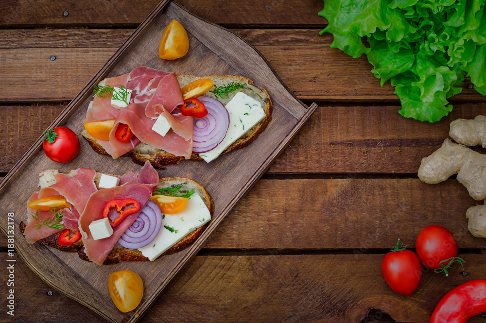 Ciabatta sandwich with salad leaves, jamon serrano and mozzarella. Top view. Selective focus. Wooden rustic background