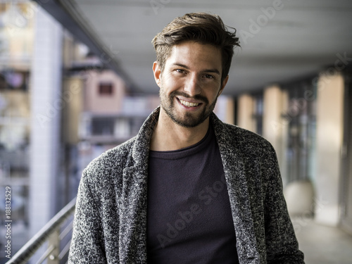 One handsome young man in urban setting in European city, standing and smiling to camera happy photo