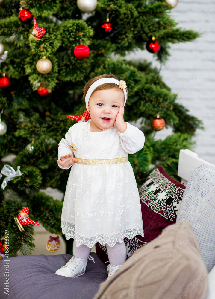 Sweet baby girl poses near a Christmas tree Sweet baby girl poses near a Christmas tree